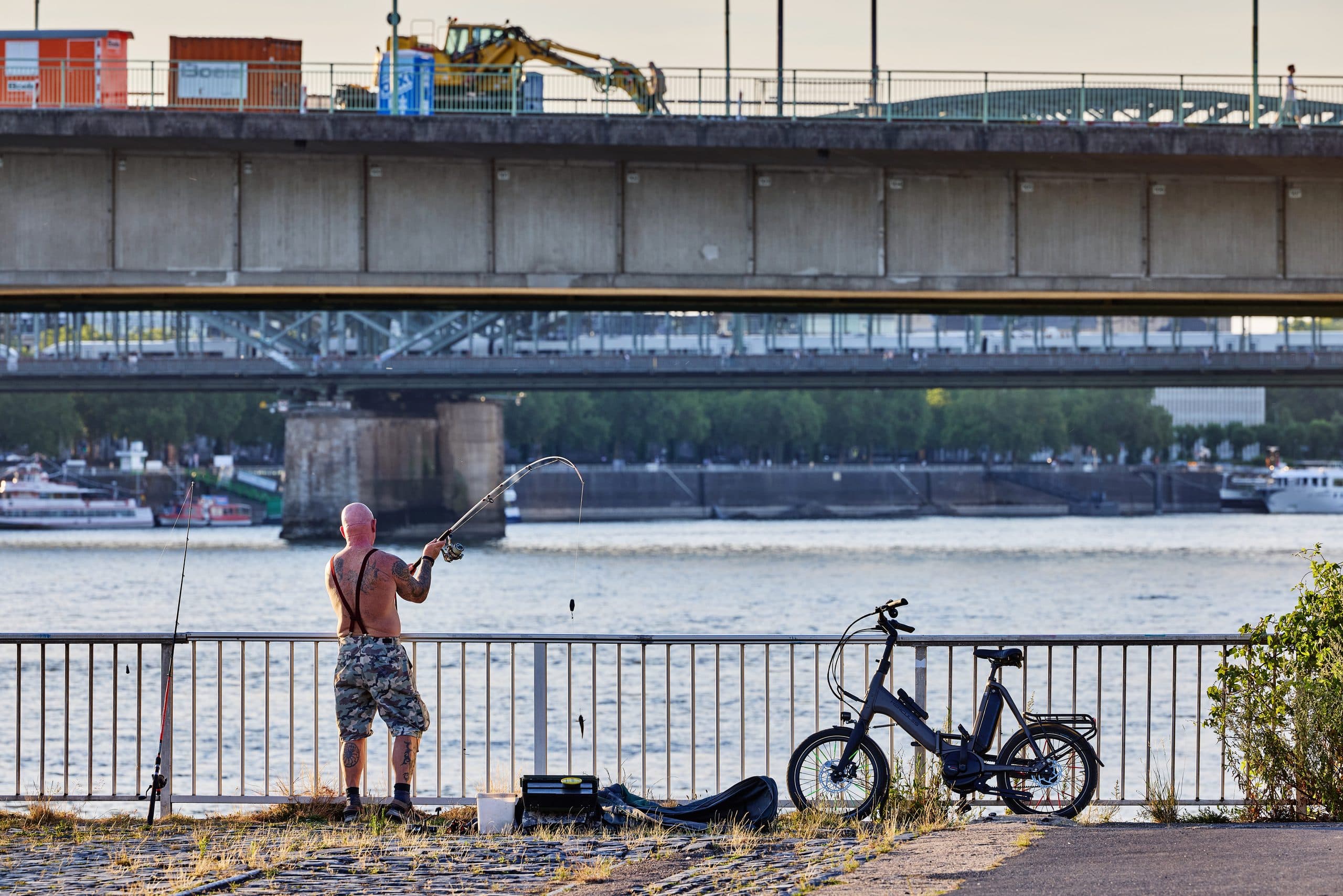 Radfahrer und E-Bike am Rheinufer in Deutz, im Hintergrund die Brücke